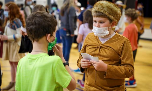 A boy dressed as a historical figure speaks to younger students